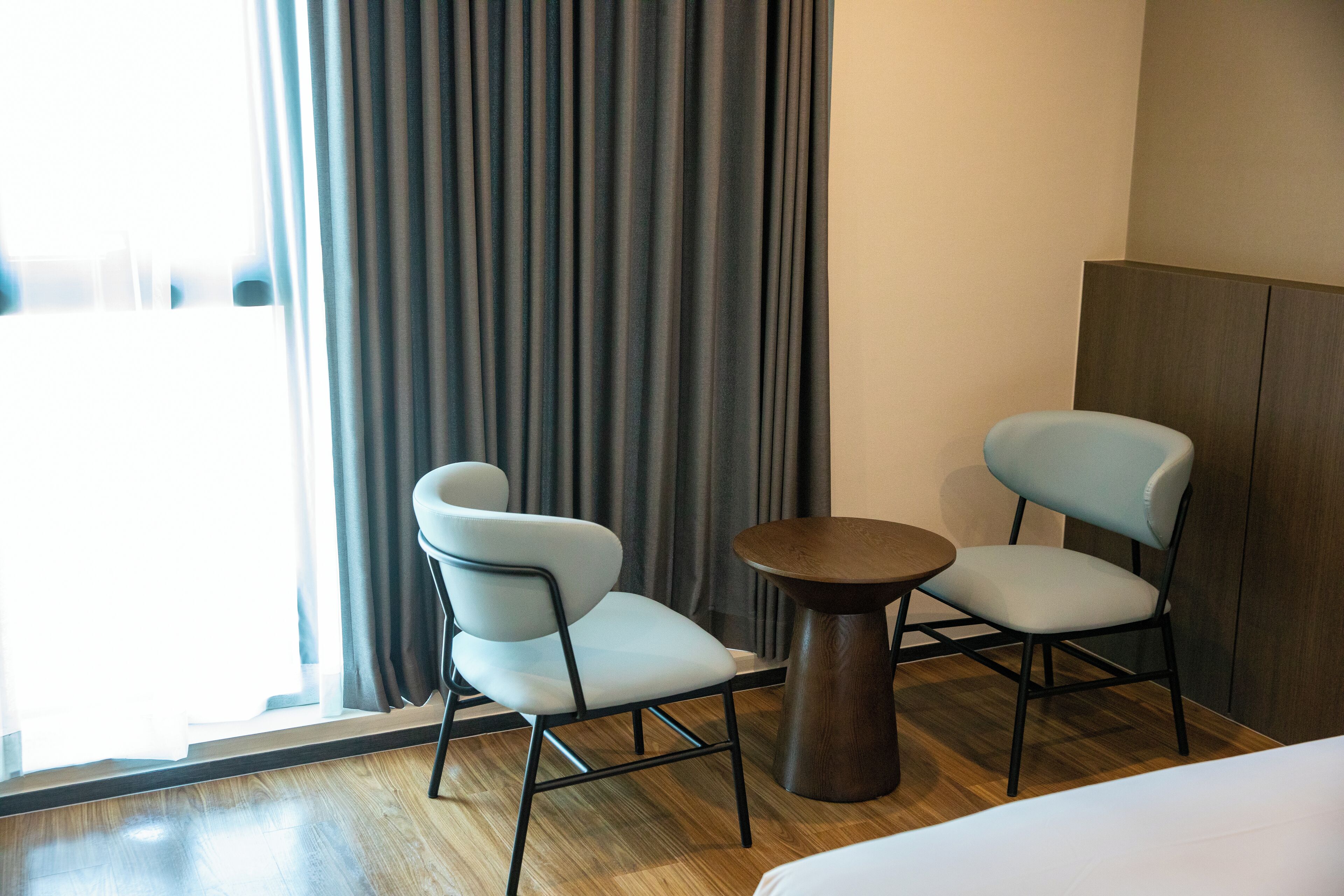 Une chambre d’hôtel avec deux chaises, une petite table ronde et un lit.