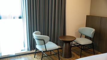 Une chambre d’hôtel avec deux chaises, une petite table ronde et un lit.