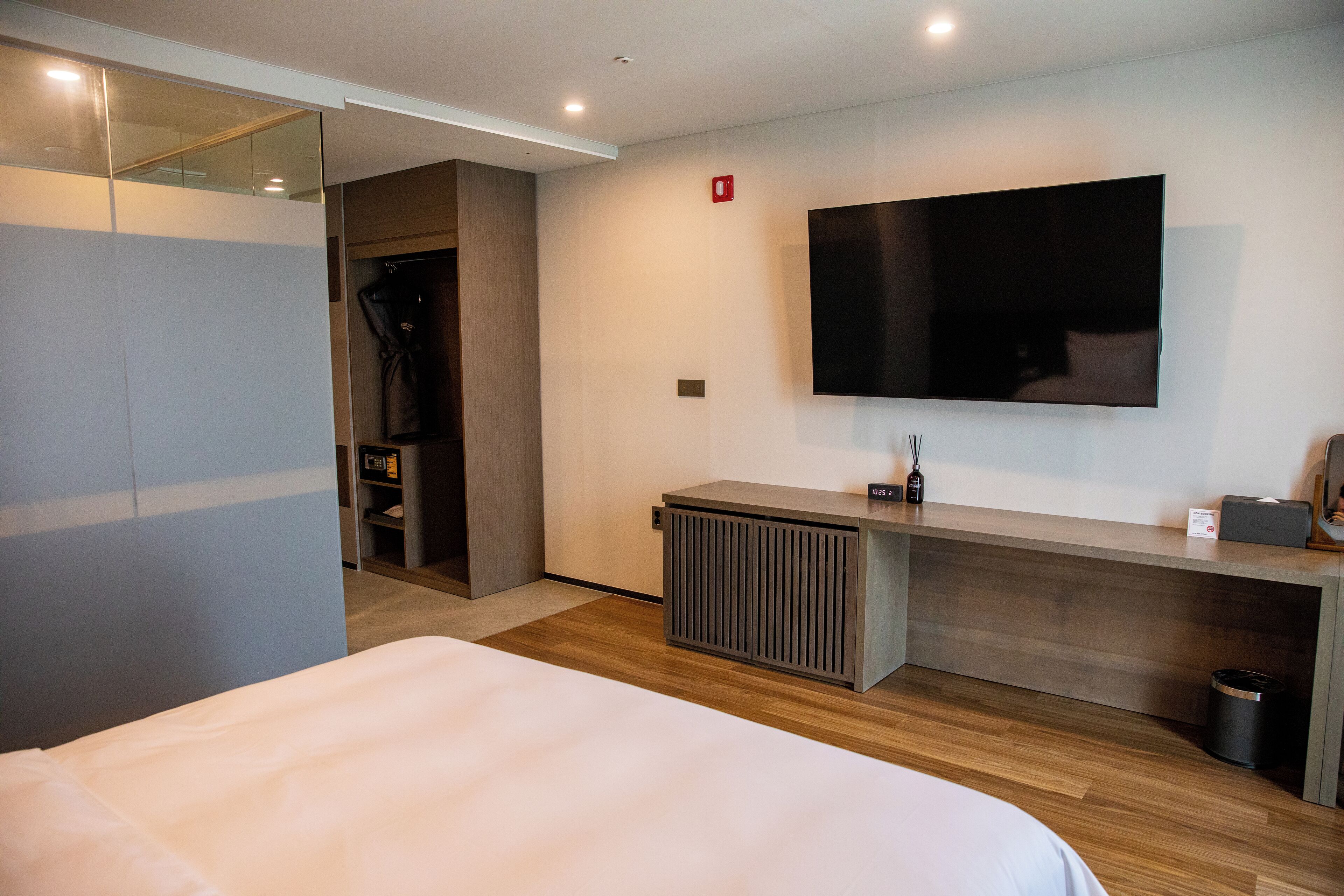 Una habitación de hotel moderna con una cama grande, un televisor de pantalla plana montado en la pared, un escritorio de madera y un radiador pequeño.