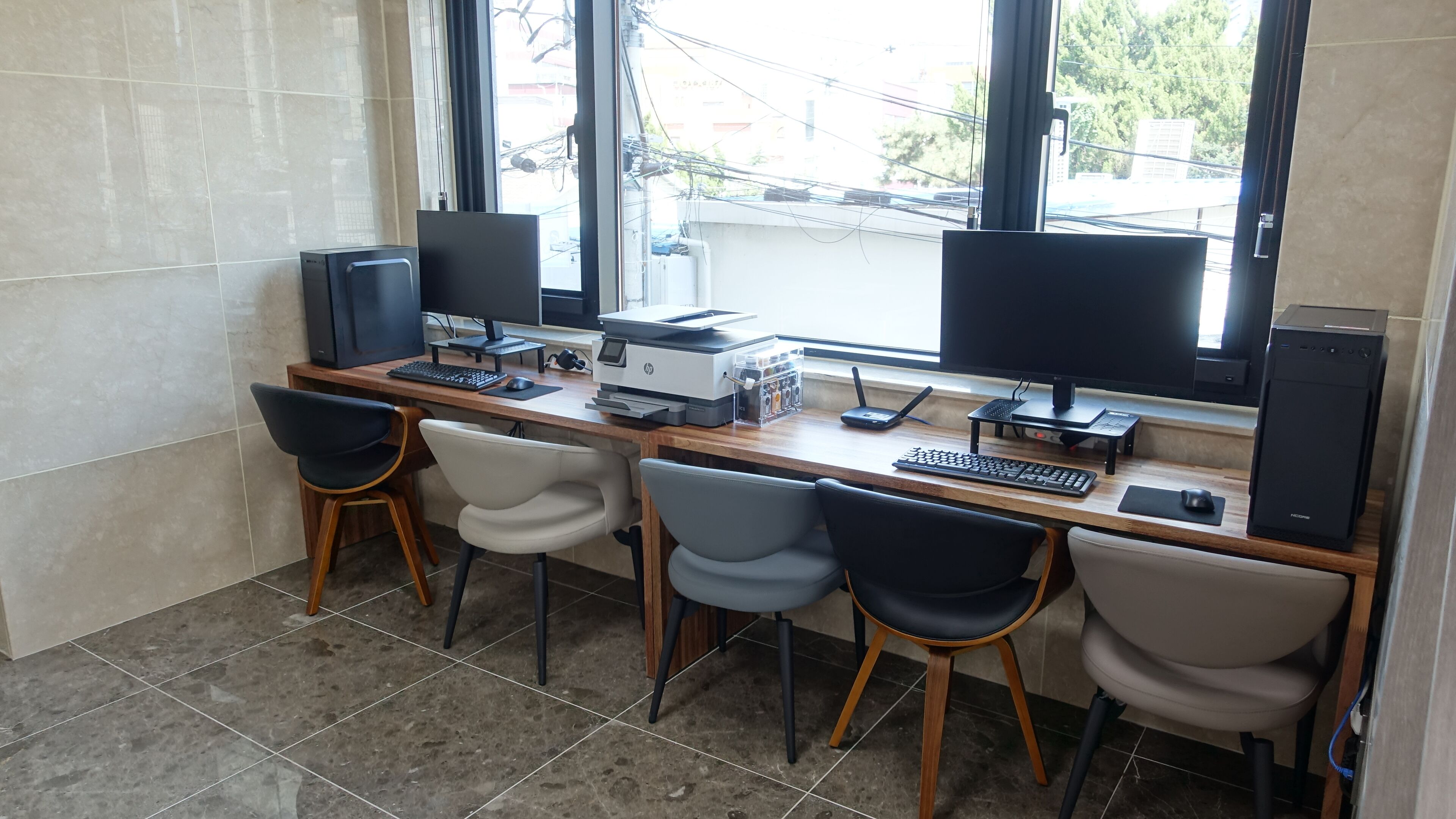 Un espace de travail équipé de deux écrans, d’une imprimante et de quatre chaises.