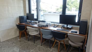 Un espace de travail équipé de deux écrans, d’une imprimante et de quatre chaises.