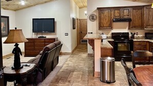 Un vaste espace de vie comprenant un canapé, un téléviseur et un plafond en bois.