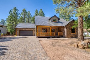 A two-story house with a garage, a covered porch, and a stone exterior.