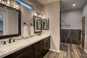 A bathroom with a marble vanity, two mirrors, and a shower area.