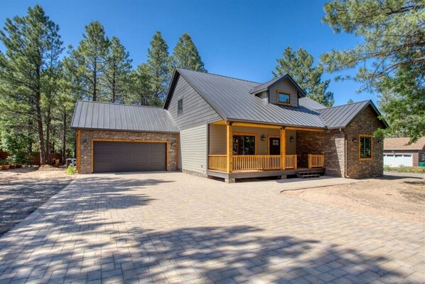 A two-story house with a garage, a covered porch, and a stone exterior.