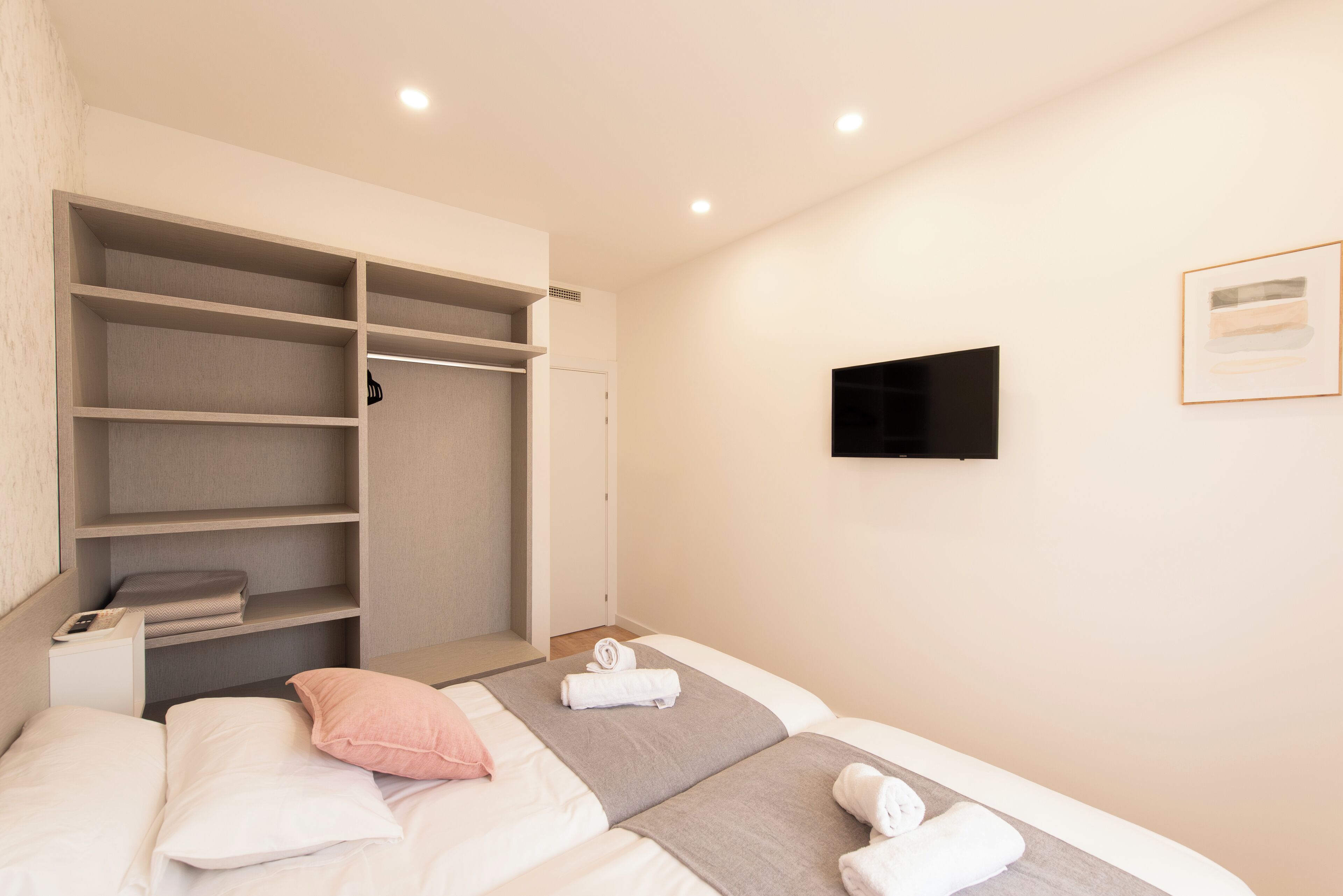 Una habitación de hotel con cama, armario, televisor y un cuadro en la pared.