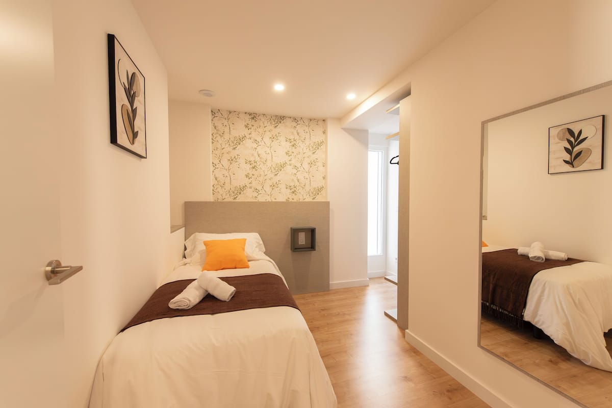 A hotel room with two beds, a large mirror, and a view of a hallway.