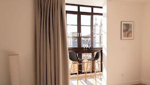 A room with a large window, two chairs, a tall floor lamp, and a framed picture on the wall.