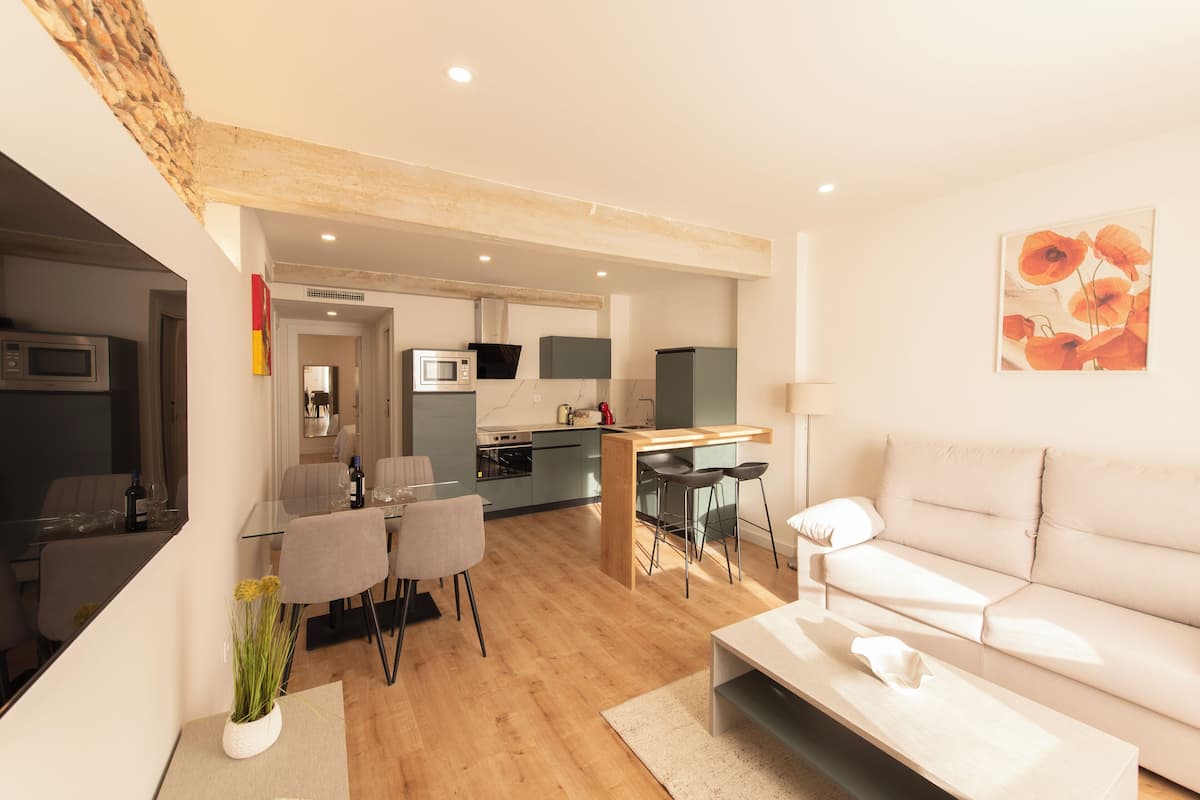 A modern living room with a sofa, a coffee table, and a dining area with chairs and a table.