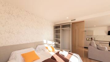 Habitación de hotel con dos camas, un sofá, un armario y una zona de cocina.