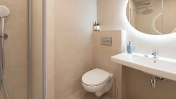 A modern bathroom with a shower, toilet, and sink.