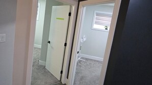 A hallway with carpeted flooring, white doors, and a dark wall. - Stylish 2BD Basement Suite Close to WEM (Edmonton)