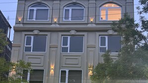 A hotel with a classic architectural style, featuring multiple windows and a well-lit entrance. - Kiwi Inn Hotel (Ujjain)