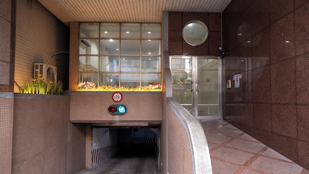 A covered pedestrian walkway with a glass entrance, a no parking sign, and a flower display. - Glory hotel (Luodong)