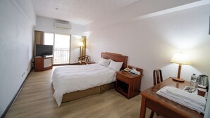 A hotel room with a bed, bedside table, lamp, and a desk with a chair. - Glory hotel (Luodong)