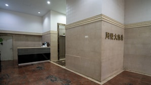 A hotel lobby with a reception desk, a wall with a sign, and a tiled floor. - Glory hotel (Luodong)