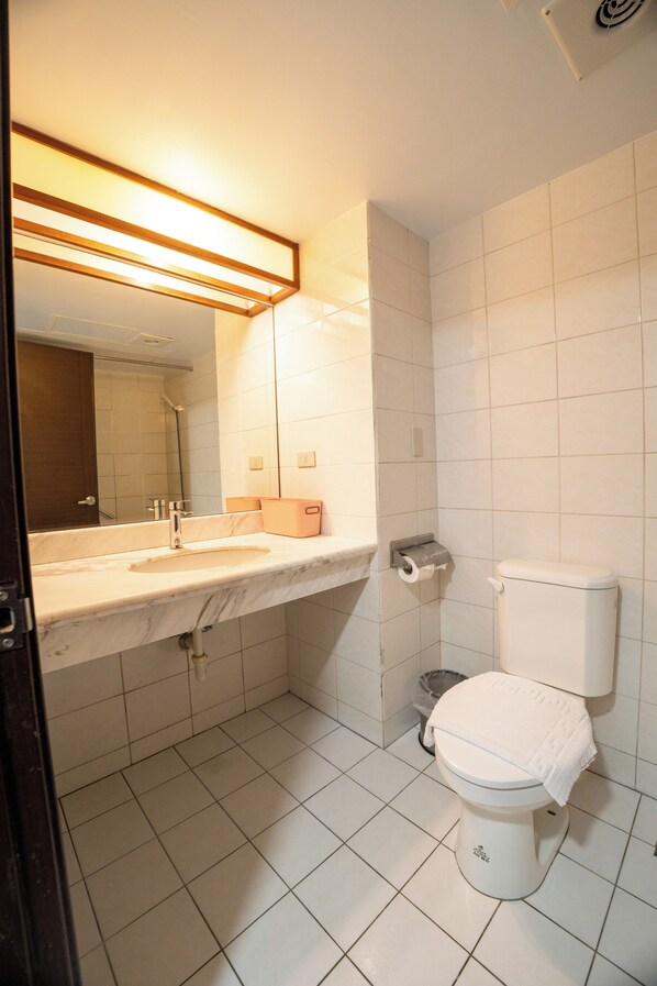 A bathroom with a white sink, mirror, and toilet. - Glory hotel (Luodong)