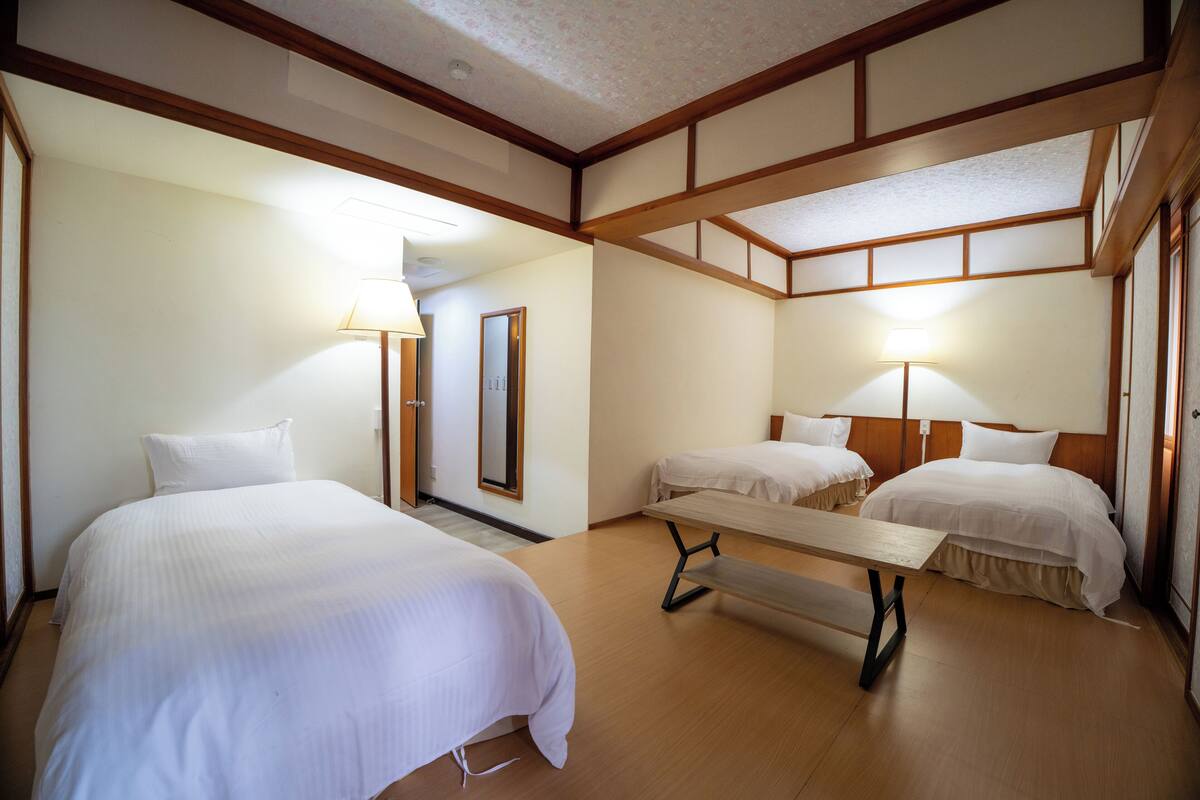 A hotel room with two beds, a wooden bench, and a mirror.