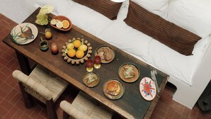 A dining area with a wooden table set for a meal, a white sofa with brown cushions, and a shelf with decorative items. - Villa Honorée - Plage des Bourdaines (Seignosse)