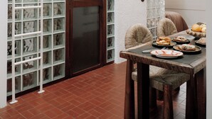 A dining area with a table set for a meal, a wooden door, and a wall with a grid of glass blocks. - Villa Honorée - Plage des Bourdaines (Seignosse)