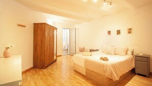 Een slaapkamer met een houten garderobe, een bed met een witte dekbedovertrek, een nachtkastje en een nachttafel.