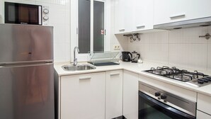 Een moderne keuken met een roestvrijstalen koelkast, een magnetron, een gasfornuis en een ingebouwde oven.