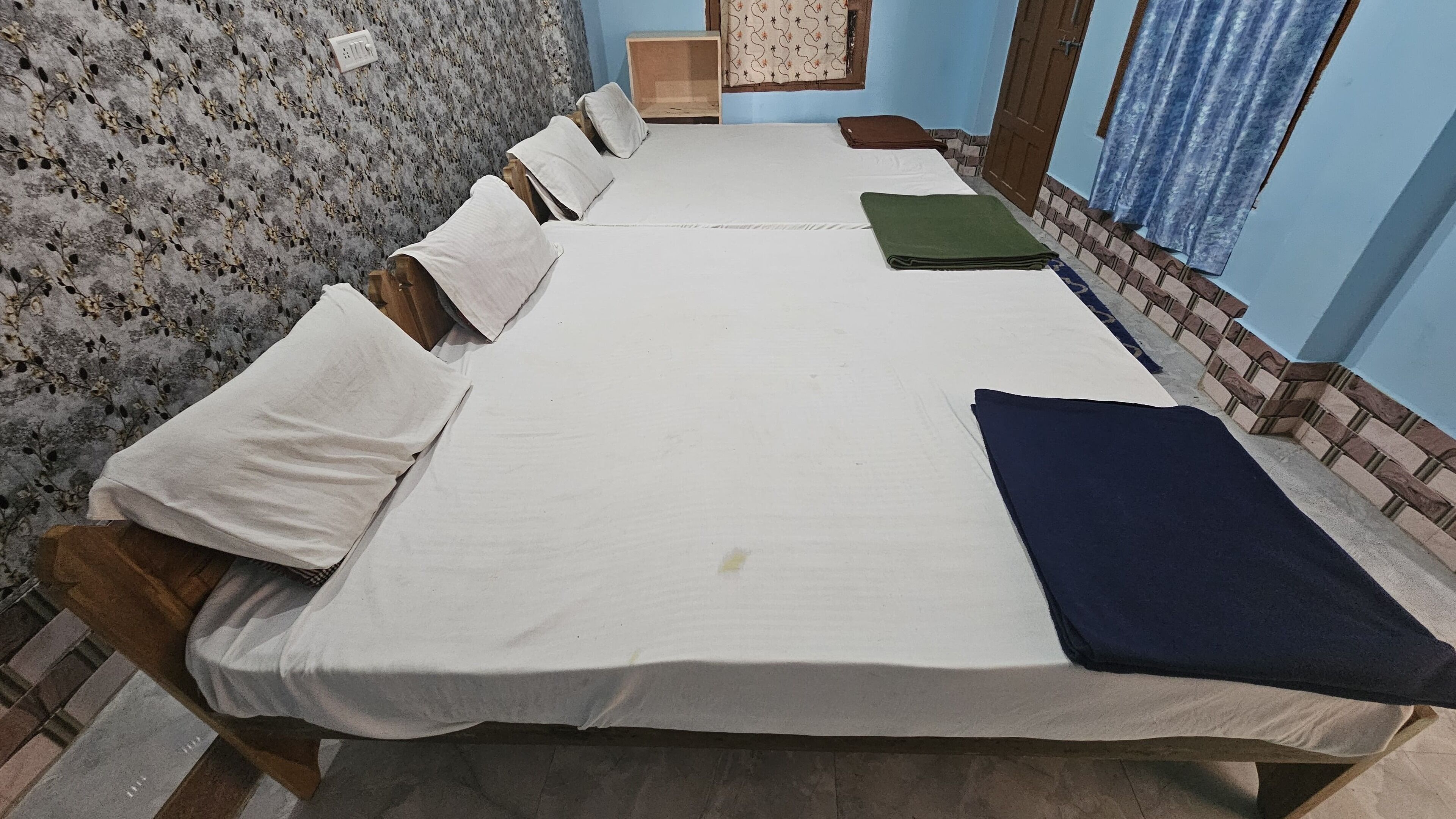 Une chambre avec un grand lit, plusieurs oreillers, un tapis vert et une tête de lit en bois.