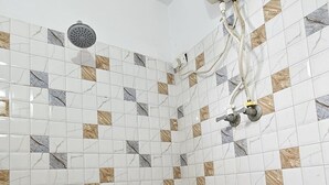 Un bany amb rajoles blanques i marrons amb dibuixos, un vàter de dutxa i un assecaguts de mans.