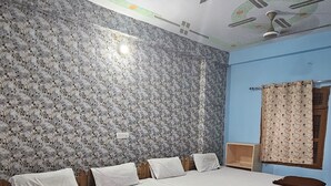 Un llit gran i ben fet amb estructura de fusta i roba de llit blanca, un ventilador de sostre i un paper pintat amb motius florals.