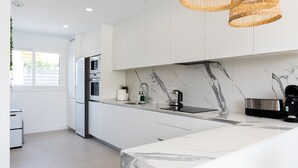 A modern kitchen with white cabinets, a marble backsplash, and a built-in oven.