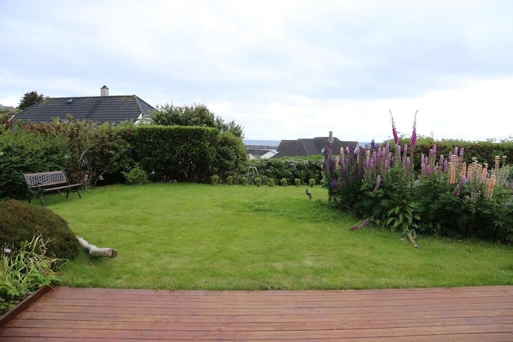 Een tuin met een houten terras, een bank en diverse planten.