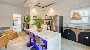 A modern kitchen with a marble island, stainless steel appliances, and a hanging light fixture.