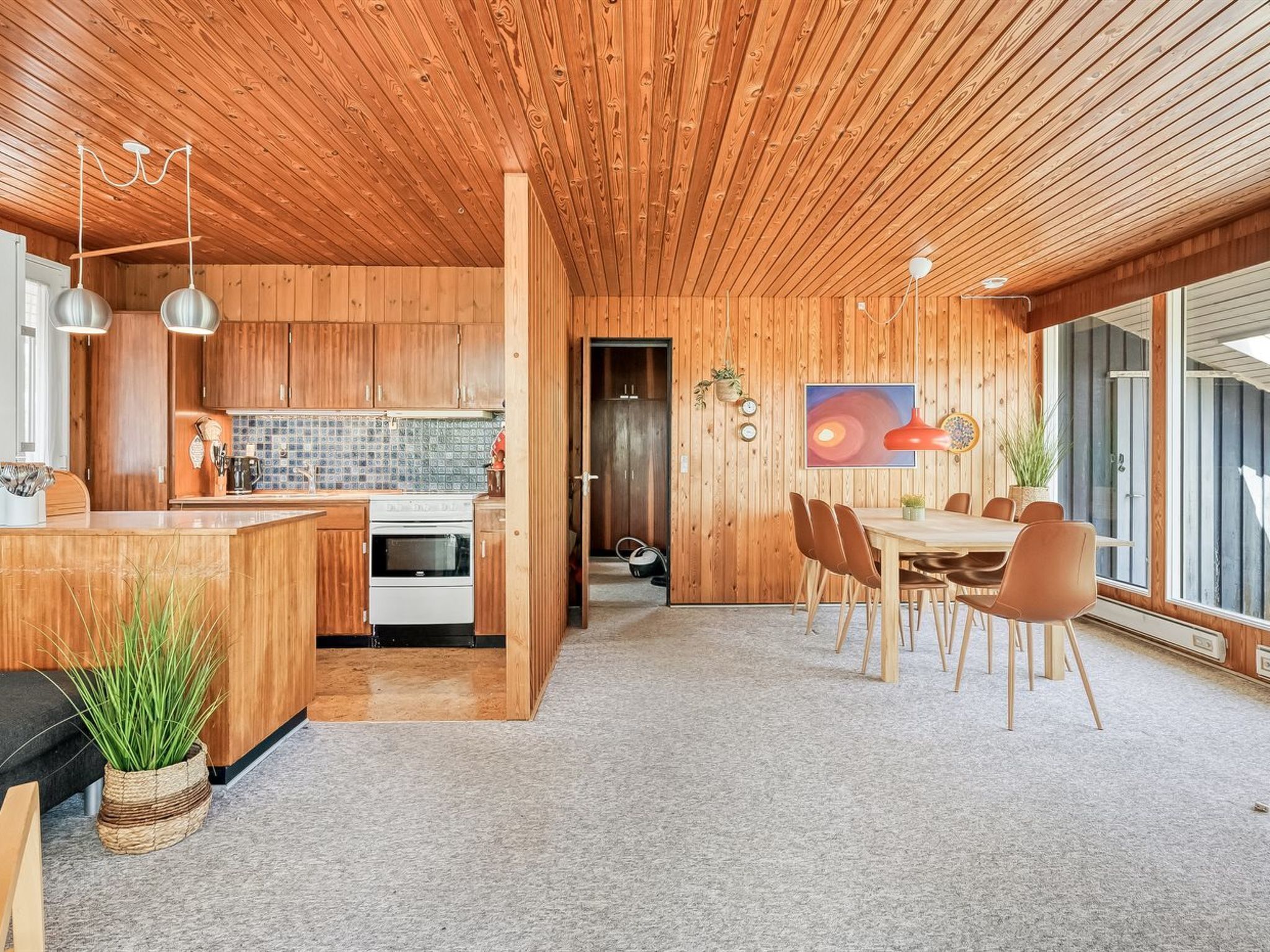 Een moderne keuken met houten kastjes, een centraal eiland en een eethoek met een tafel en stoelen.