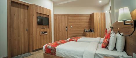 A bedroom with two beds, wooden wardrobes, a television, and a ceiling fan.