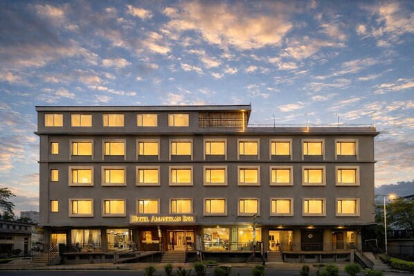 A multi-story hotel with a flat facade, evenly spaced windows, and a sign reading "Hotel Amanran Inn". - Hotel Amantran Inn - City Centre (Udaipur)