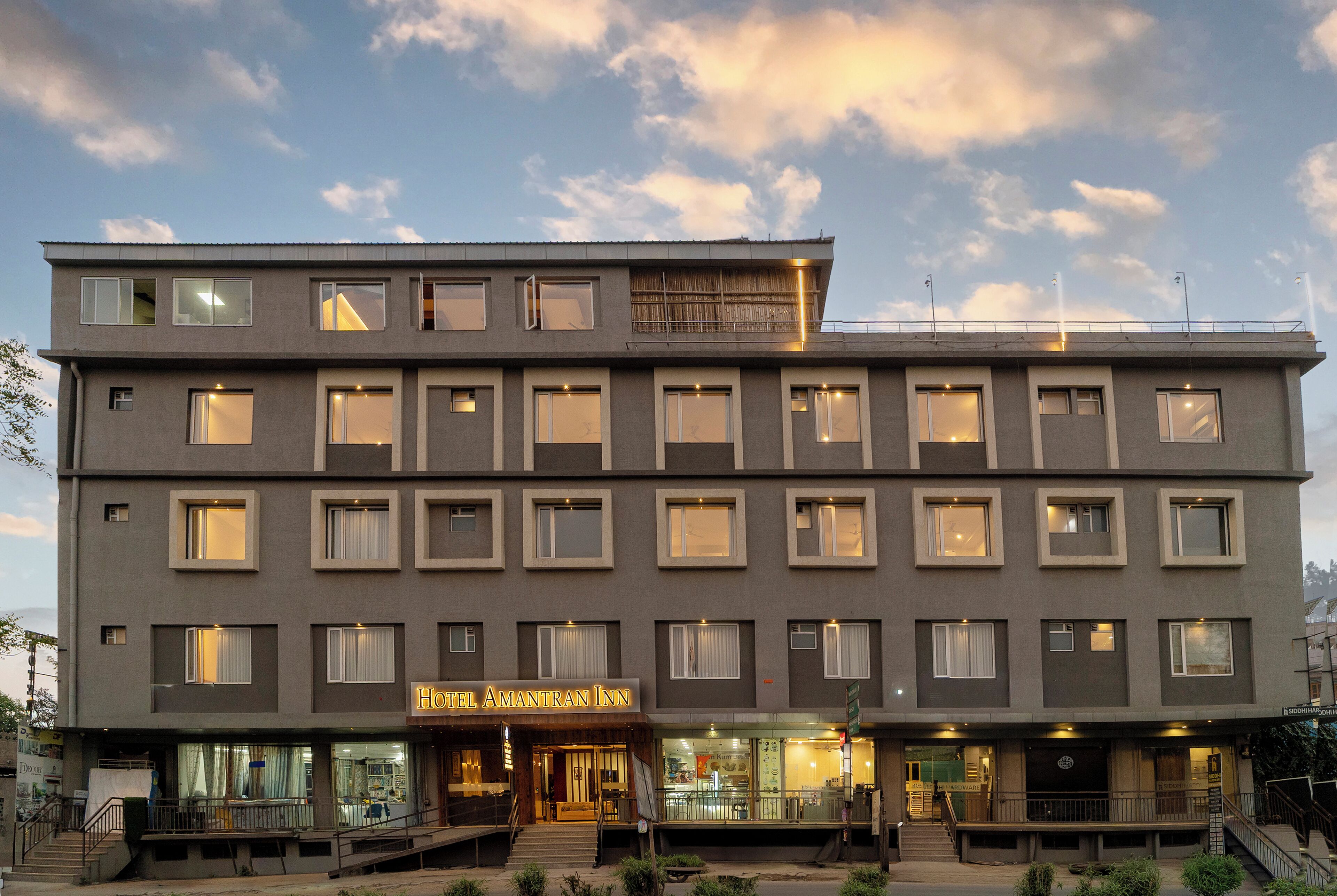 Un hotel de varios pisos con fachada plana, múltiples ventanas y un letrero que dice 'Hotel Amantran Inn'.