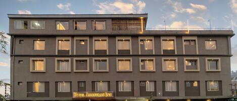Un hotel de varios pisos con fachada plana, múltiples ventanas y un letrero que dice 'Hotel Amantran Inn'.