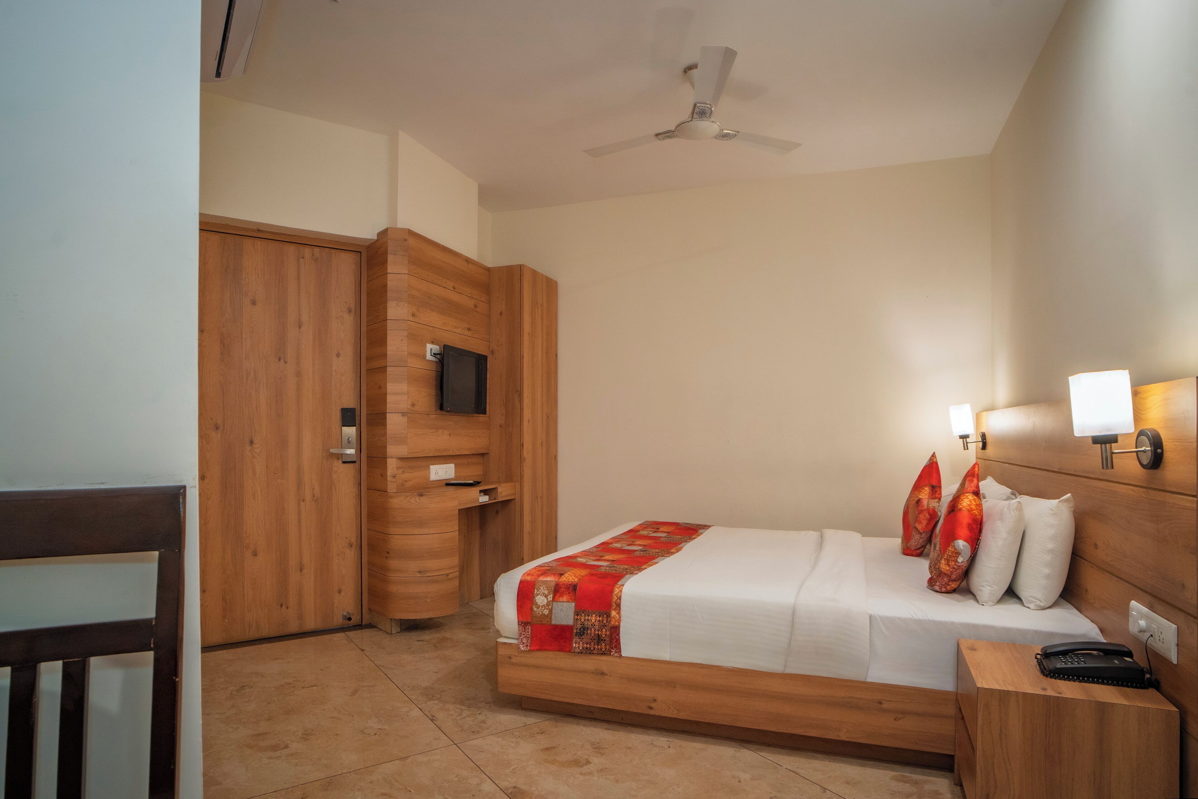 A bedroom with a wooden bed, a nightstand, a desk, and a wardrobe.