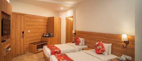 A hotel room with two beds, wooden walls, a ceiling fan, a bedside table with a lamp, and a TV on a shelf.