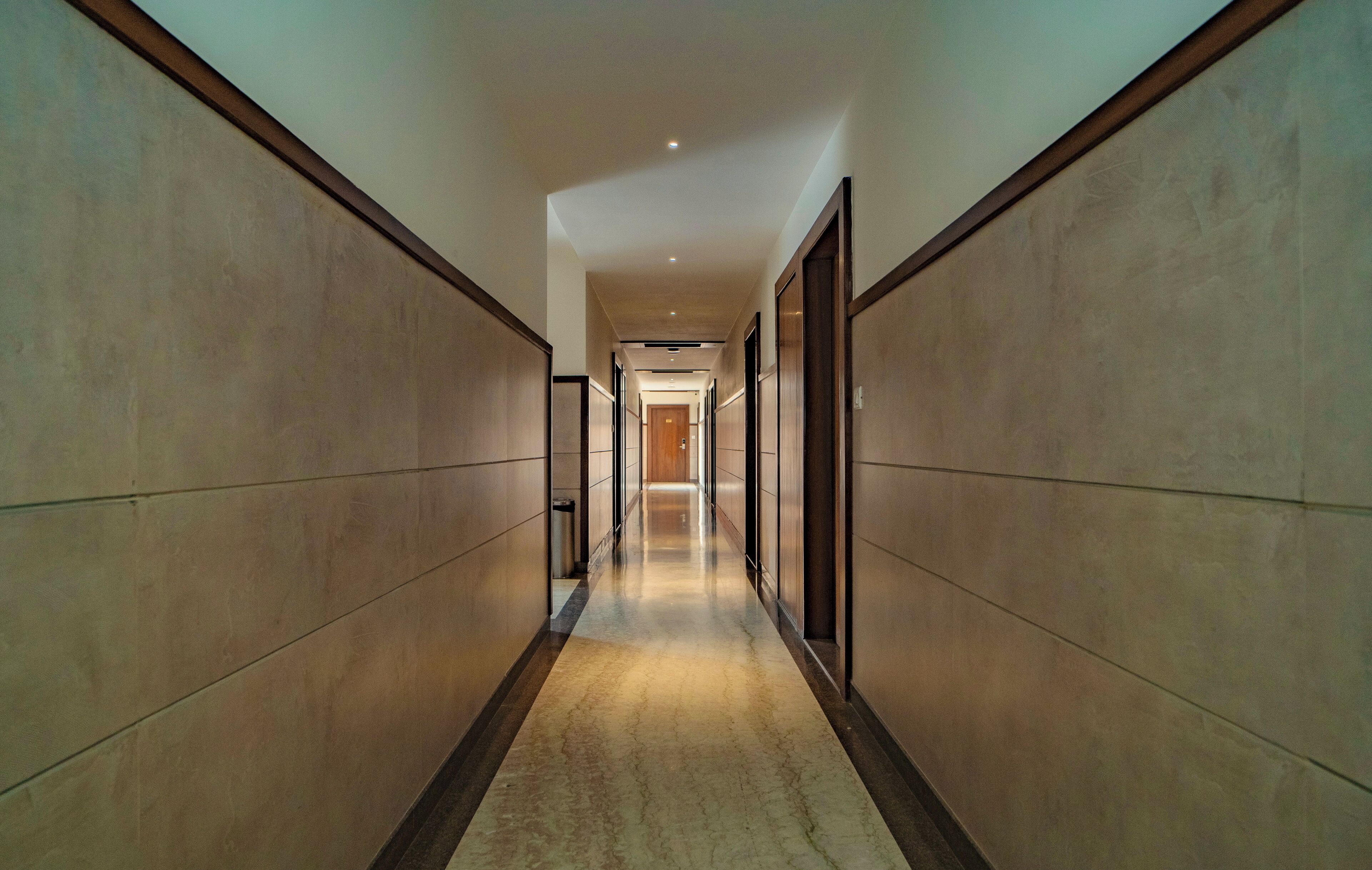 A long, narrow hallway with a marble floor and wooden paneling on the walls.
