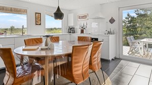 Una cocina moderna con una isla grande, armarios blancos y vistas al exterior.