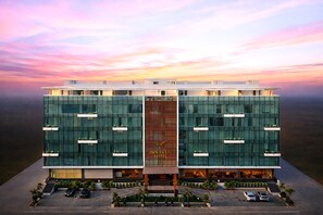 A modern hotel with a central vertical entrance, multiple balconies, and a parking area. - TOWN SQUARE SUITES (Hyderabad)