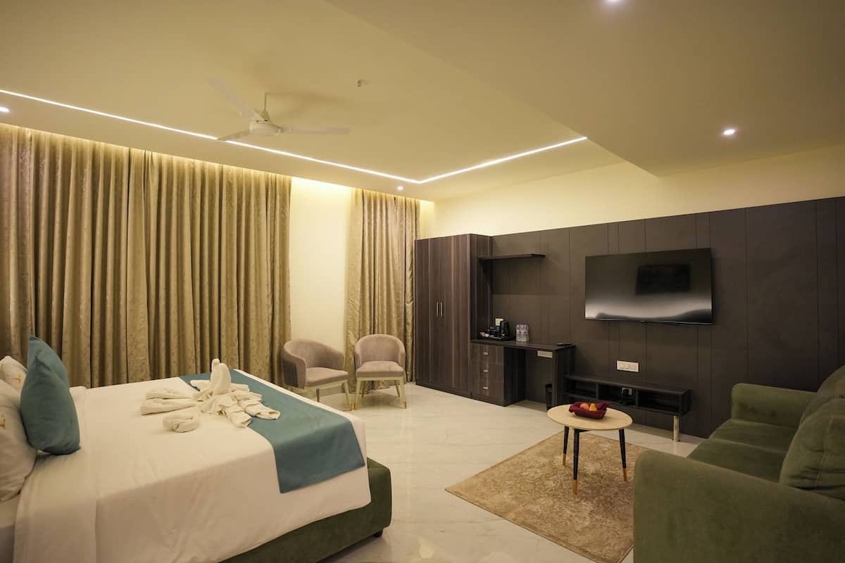 A hotel room with a bed, a TV, a desk, and a seating area.