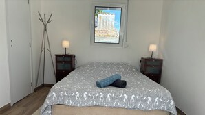 A bedroom with a bed, two bedside tables, a window with a view, and a floor lamp. - Herdade Palma T1p (country house) (Moita)