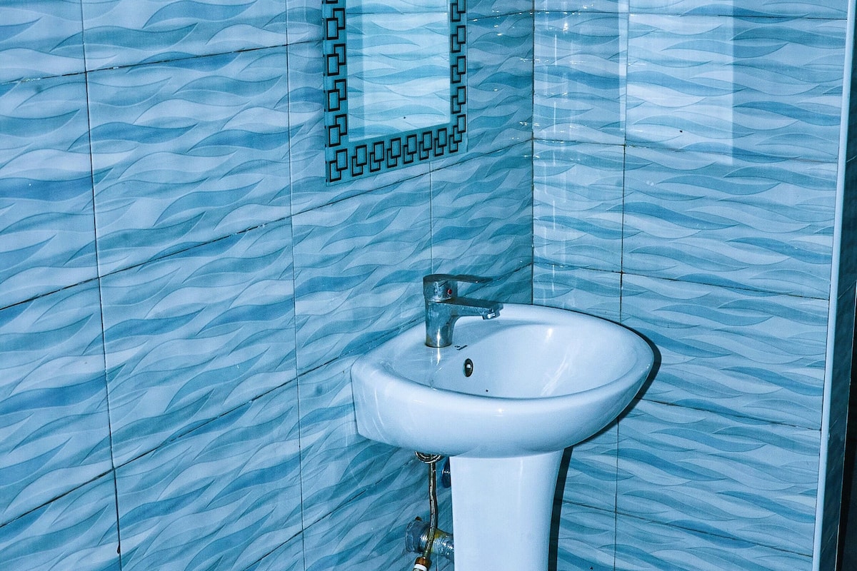 Ein Badezimmer mit einem weißen Waschbecken und einem Spiegel mit schwarzem Rahmen.