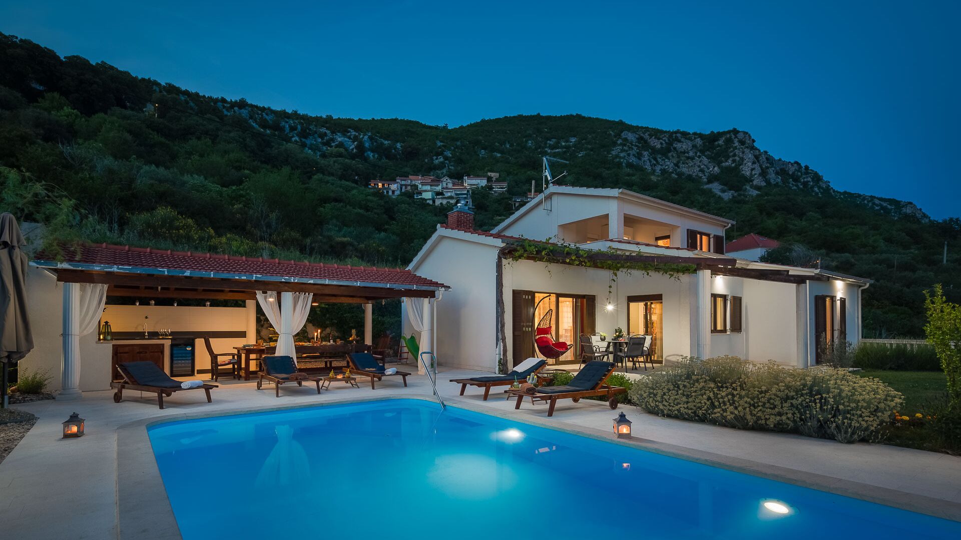 Una casa de dues plantes amb piscina, zona d'estar a l'exterior i vistes als turons del voltant.
