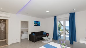 A modern living room with a sofa, a coffee table, and a view of the sea through large windows. - Apartman Mia 2 - Omiš by Villas Guide (Mimice)