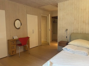 A bedroom with a bed, a desk with a chair, a wardrobe, and a mirror.