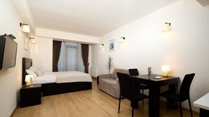 A hotel room with a bed, a desk with chairs, a TV, and a window with curtains. - MaRKoS Flat in Block 1, New Gudauri (Gudauri)