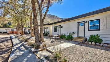 A single-story building with a front porch, a small outdoor seating area, and a gravel driveway.